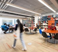 People sitting at tables and walking in the Sara Miller McCune Arts Library