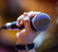 A hand holding a microphone to speak.