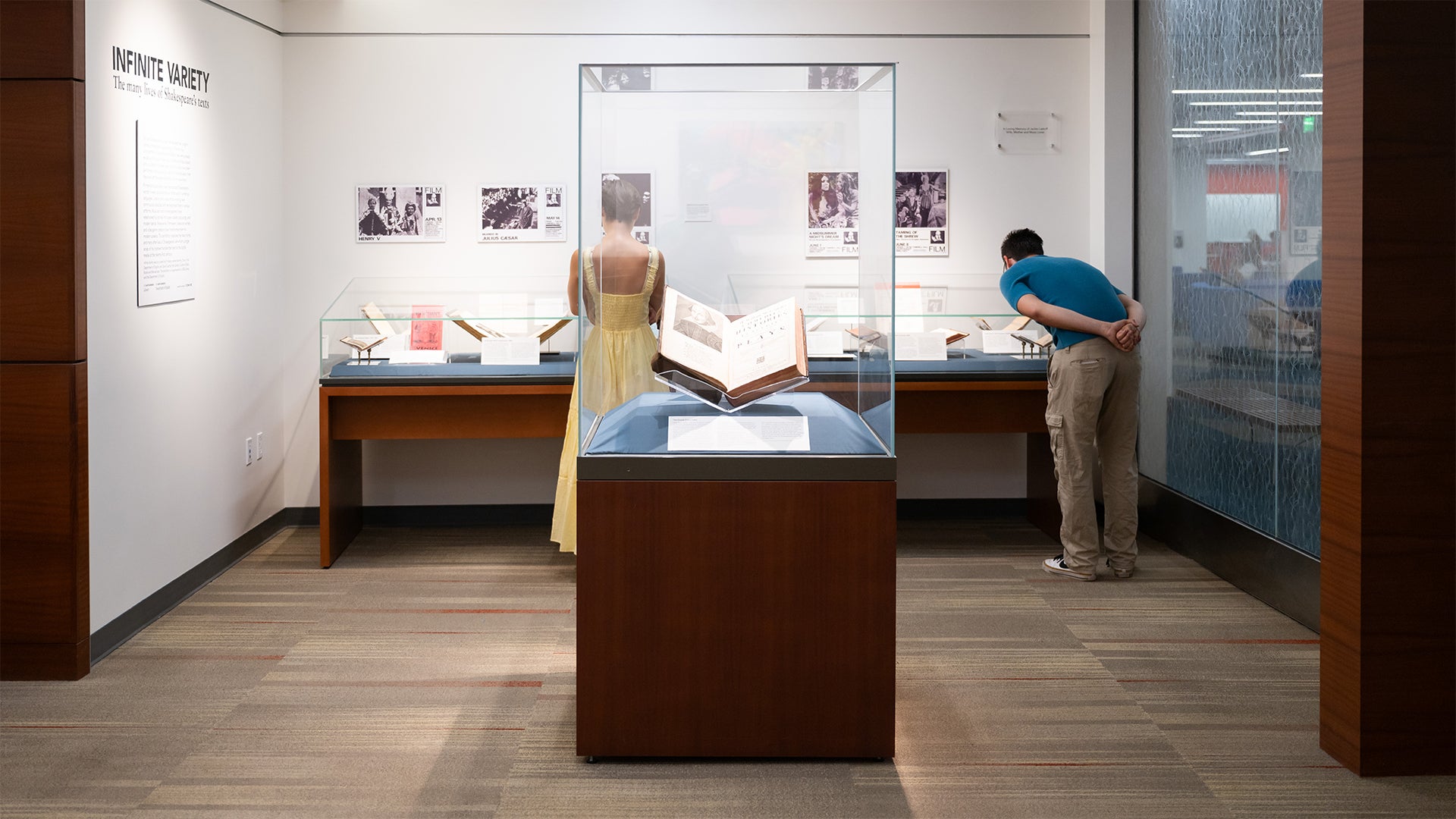 Two UCSB students stand in the Laskoff Exhibition Alcove, looking closely at historical materials on display as part of the Infinite Variety exhibition.