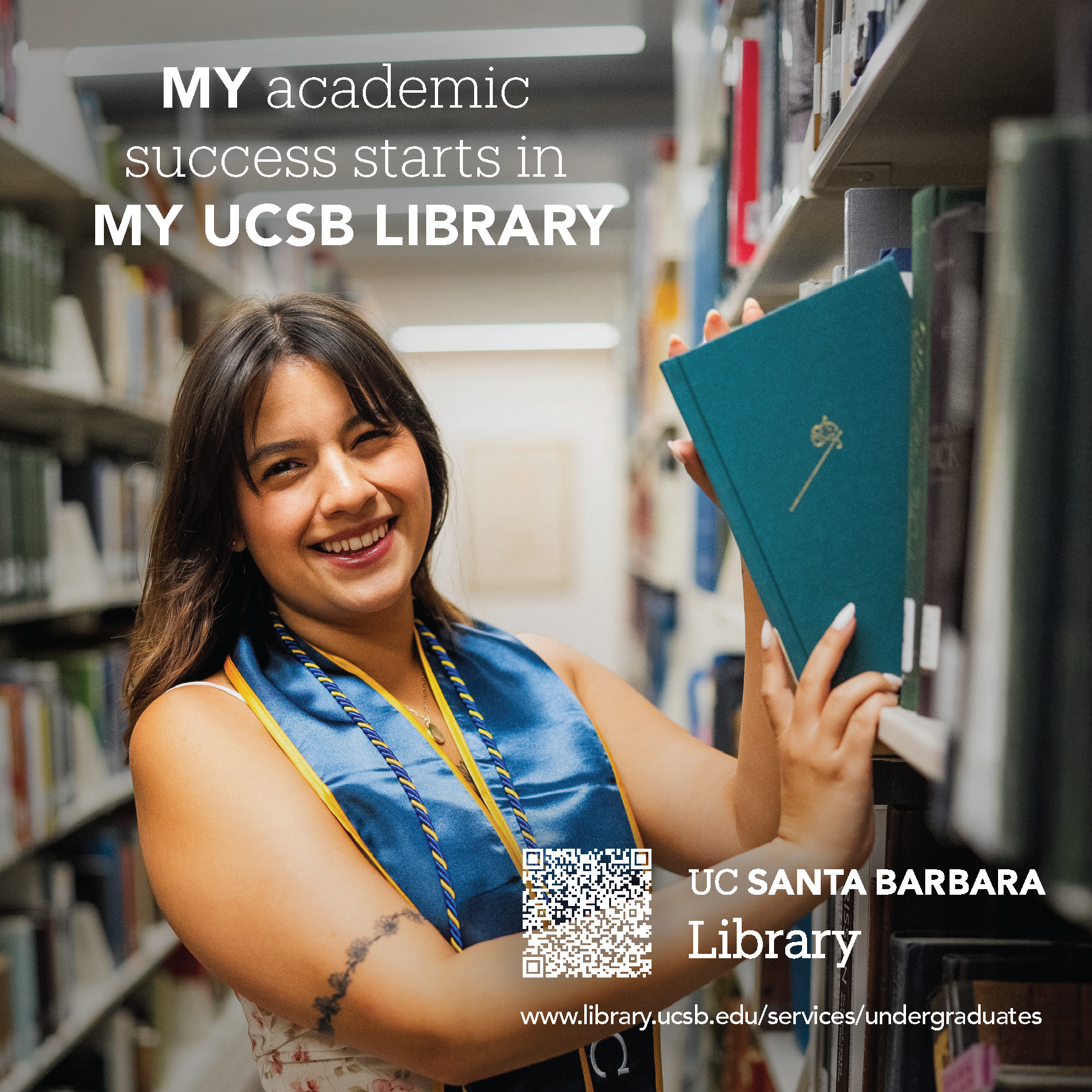 UCSB student with graduation stole standing next to a Library bookshelf holding a book